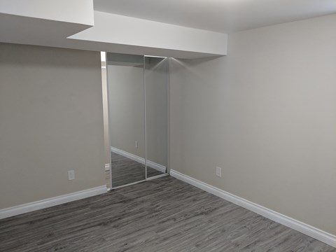 a bedroom with a mirrored closet and a wood floor